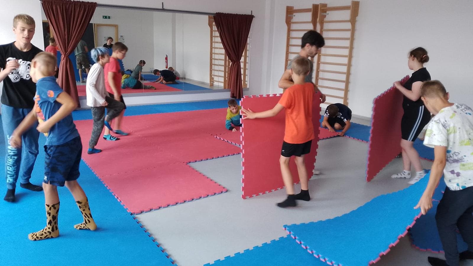 Děti při pohybové hře s žíněnkami v tělocvičně